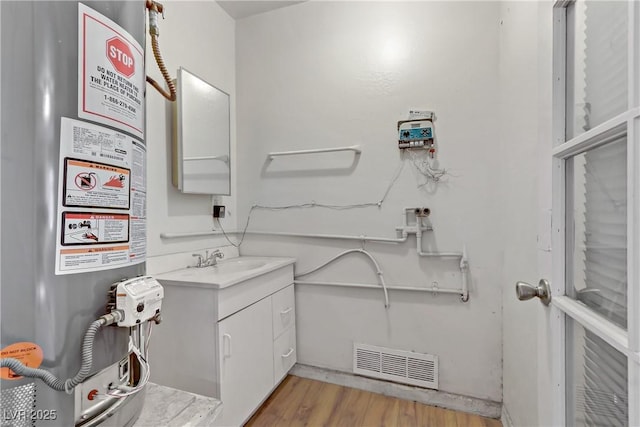 bathroom featuring gas water heater, visible vents, wood finished floors, and vanity