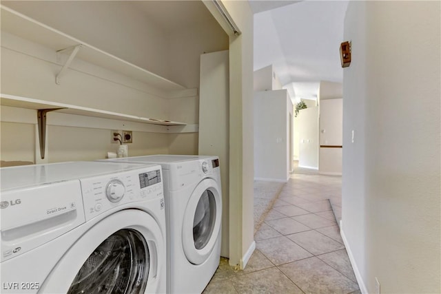 clothes washing area with light tile patterned floors, laundry area, baseboards, and washing machine and clothes dryer