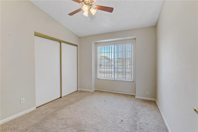 unfurnished bedroom with a closet, carpet floors, baseboards, and vaulted ceiling