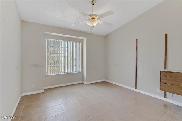 spare room with light tile patterned floors, baseboards, a textured ceiling, and a ceiling fan