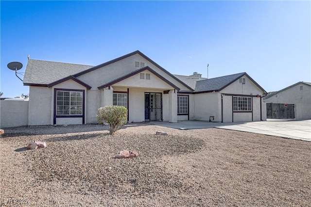 view of front of house featuring a patio area, fence, and stucco siding