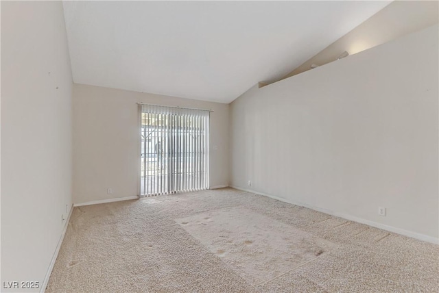 unfurnished room featuring baseboards, lofted ceiling, and carpet