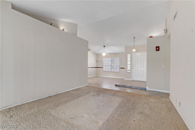 carpeted empty room with baseboards, visible vents, ceiling fan, tile patterned flooring, and vaulted ceiling