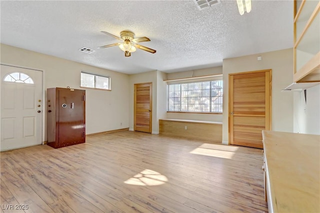 foyer entrance with visible vents, ceiling fan, and light wood finished floors