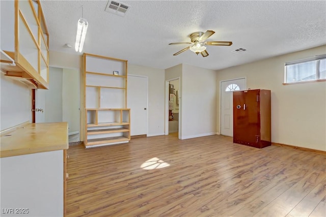 unfurnished living room with visible vents, a ceiling fan, and wood finished floors