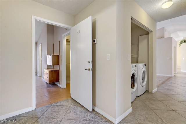 laundry room with a textured ceiling, light tile patterned floors, baseboards, and washing machine and clothes dryer