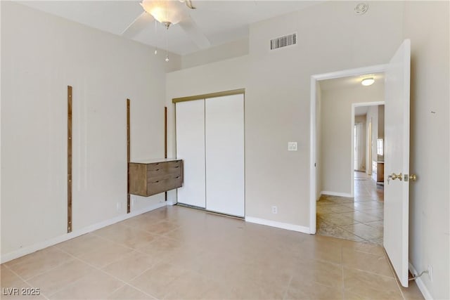 unfurnished bedroom featuring baseboards, visible vents, light tile patterned flooring, a closet, and a towering ceiling