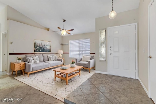 living area featuring tile patterned floors, ceiling fan, baseboards, and lofted ceiling