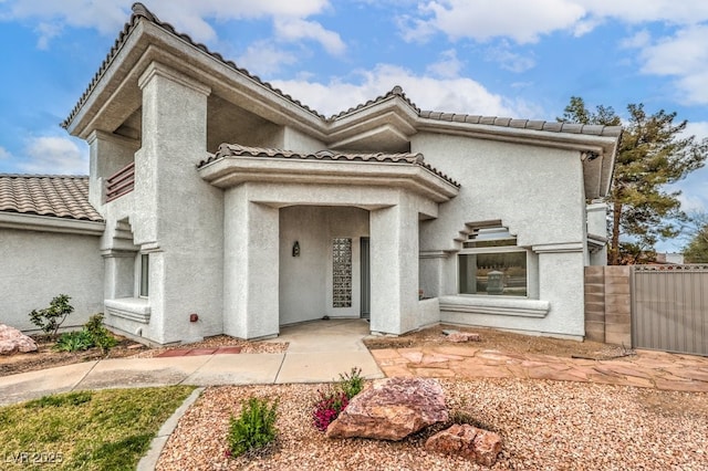 view of front of home with stucco siding, fence, and a tiled roof