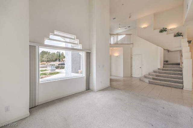 unfurnished living room featuring stairway, a high ceiling, carpet, and tile patterned floors