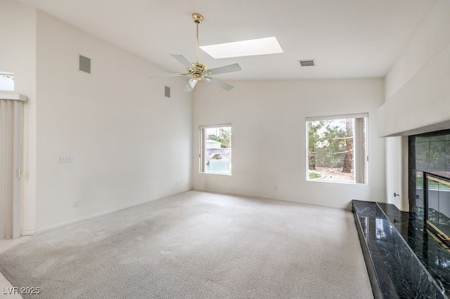 unfurnished living room with high vaulted ceiling, a tile fireplace, a skylight, and visible vents