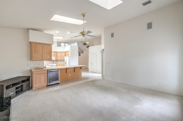 3710 E Oquendo Rd, Las Vegas, NV 89120 - kitchen with a skylight, wine cooler, white appliances, light brown cabinetry, and a peninsula