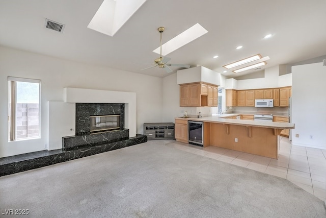 kitchen with white microwave, visible vents, beverage cooler, open floor plan, and a premium fireplace