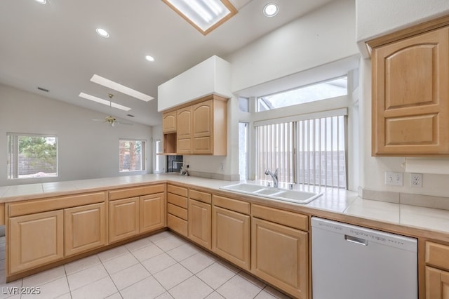 kitchen with lofted ceiling with skylight, light brown cabinets, a sink, a peninsula, and white dishwasher