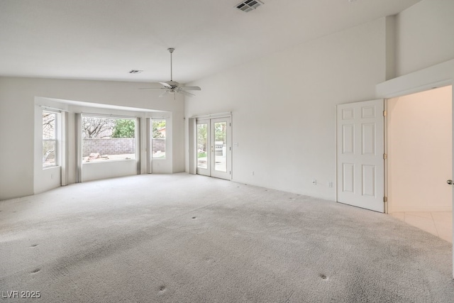 empty room with french doors, visible vents, carpet floors, and high vaulted ceiling