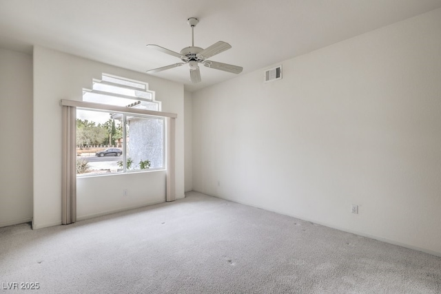 carpeted spare room featuring plenty of natural light, a ceiling fan, and visible vents