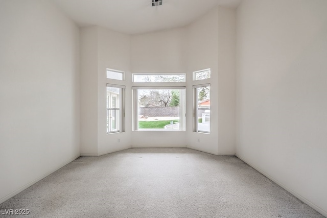 carpeted empty room with visible vents and a towering ceiling