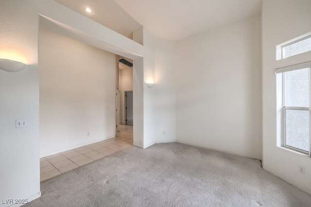 empty room featuring light tile patterned flooring, visible vents, and light colored carpet