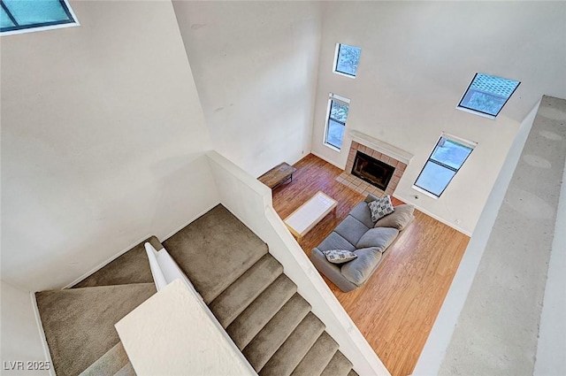 stairs with a fireplace, wood finished floors, and a towering ceiling