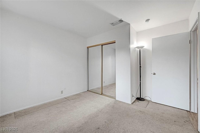 unfurnished bedroom with visible vents, light carpet, and a closet