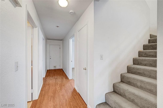 hall with light wood-type flooring, visible vents, and stairway