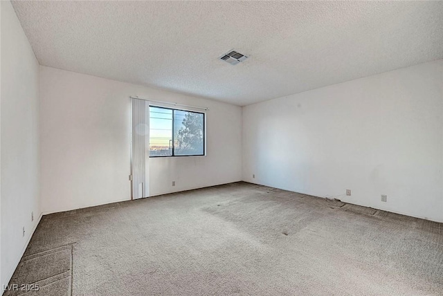 carpeted empty room with visible vents and a textured ceiling