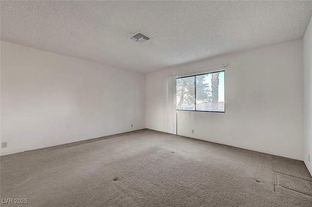 spare room featuring visible vents, a textured ceiling, and carpet floors