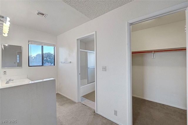 full bath with vanity, a shower with shower door, baseboards, visible vents, and a spacious closet