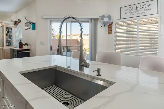 kitchen featuring a sink and light stone countertops