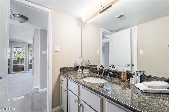 bathroom with visible vents, baseboards, a textured ceiling, and vanity