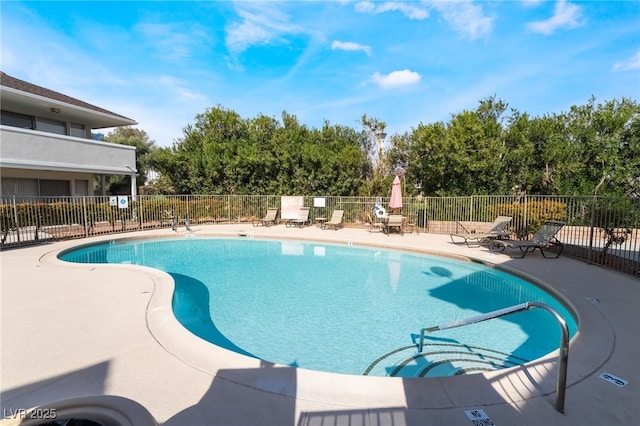 community pool with a patio area and fence