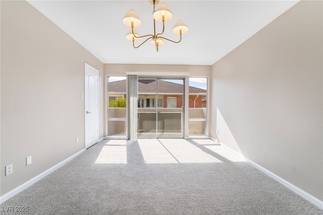 carpeted empty room with baseboards and a chandelier