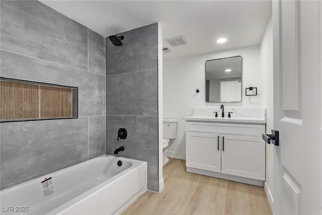 bathroom with vanity, wood finished floors, visible vents, baseboards, and toilet