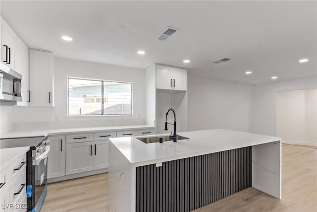 kitchen with visible vents, appliances with stainless steel finishes, light wood-type flooring, and a sink