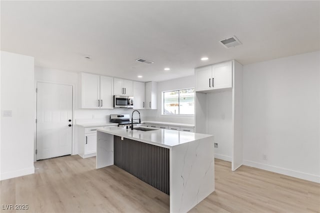 kitchen featuring a sink, a kitchen island with sink, visible vents, and stainless steel appliances