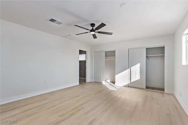 unfurnished bedroom with visible vents, ceiling fan, baseboards, multiple closets, and light wood-type flooring