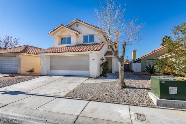 mediterranean / spanish house featuring stucco siding, a tiled roof, concrete driveway, and fence