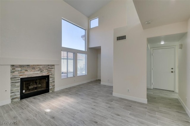 unfurnished living room with light wood-style floors, a fireplace, visible vents, and baseboards