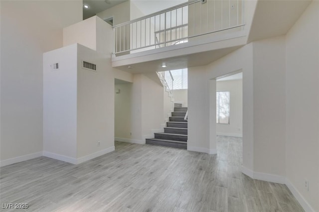 interior space featuring a high ceiling, wood finished floors, visible vents, and baseboards