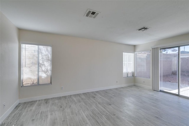 spare room with visible vents, plenty of natural light, and light wood-style flooring