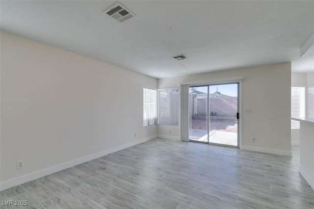 spare room with visible vents, plenty of natural light, and light wood-style floors