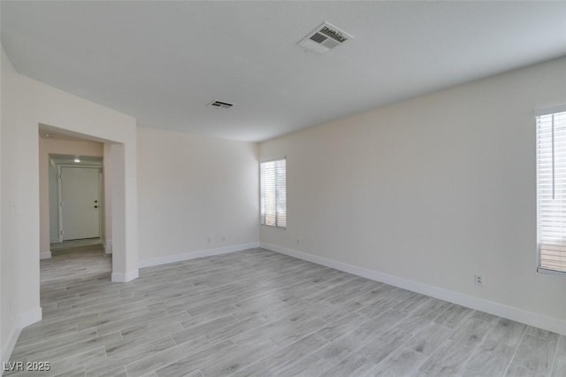 unfurnished room with a healthy amount of sunlight, visible vents, and light wood-type flooring