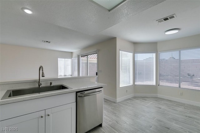 kitchen with visible vents, light wood finished floors, a sink, light countertops, and dishwasher