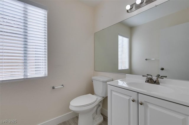 half bathroom featuring vanity, toilet, and baseboards