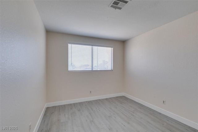 empty room featuring visible vents, baseboards, and light wood finished floors