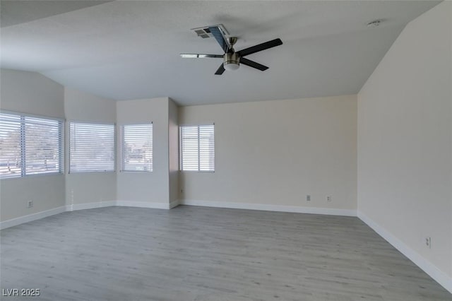 spare room featuring visible vents, wood finished floors, baseboards, ceiling fan, and vaulted ceiling