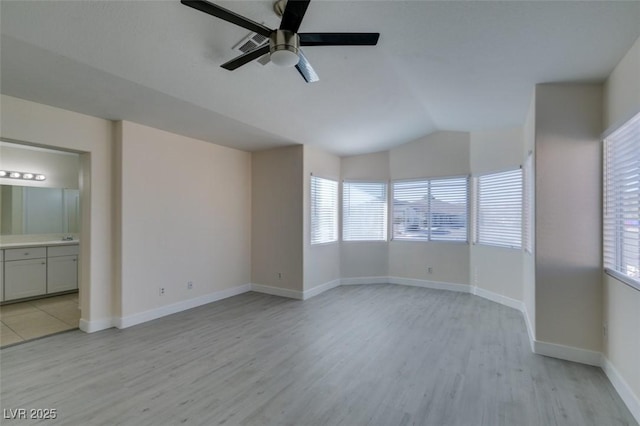 spare room featuring a ceiling fan, lofted ceiling, light wood-style floors, and baseboards