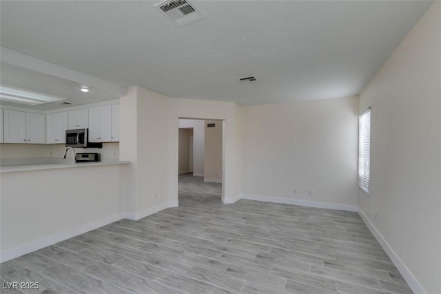 interior space with visible vents, light wood-style flooring, and baseboards