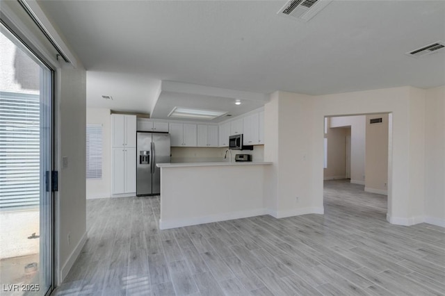 kitchen featuring stainless steel appliances, light wood finished floors, visible vents, and light countertops