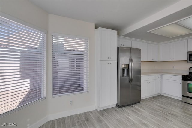 kitchen featuring light wood-type flooring, stainless steel appliances, white cabinets, and light countertops